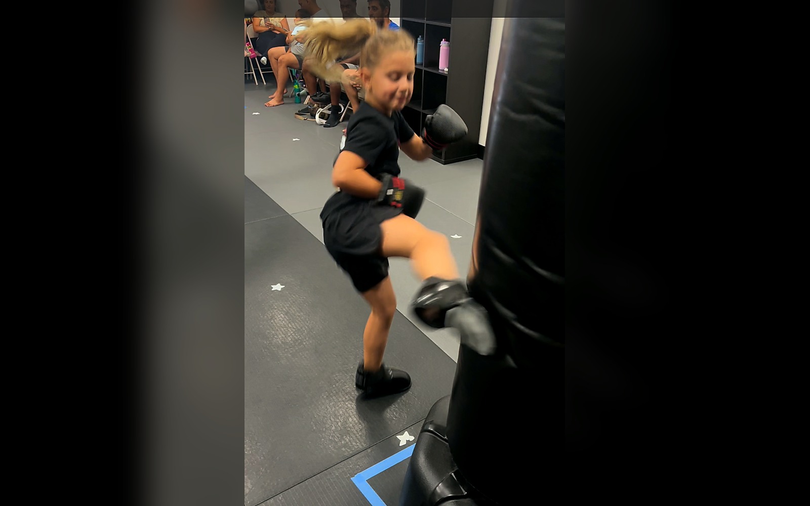 Girl in training gear kicking a heavy bag at the Las Vegas kids martial arts studio